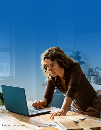 A woman working at her laptop on her kitchen counter